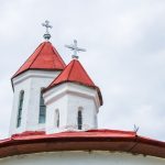 Kereszttel díszített kápolna tető – fehér falak, vörös fedés, felhős idő